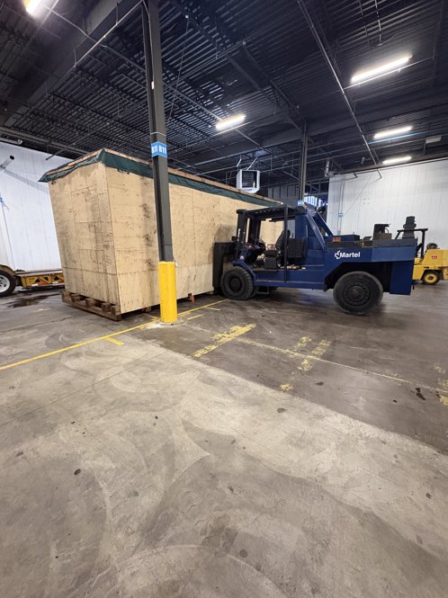 Industrial machinery being handled outdoors near a warehouse