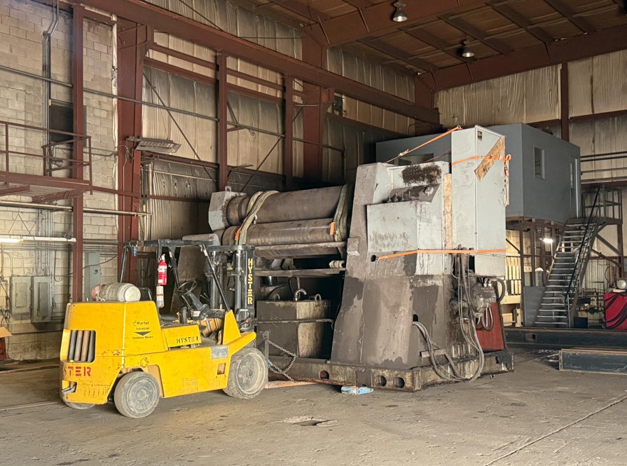 Large industrial machine and heavy forklift inside a manufacturing facility